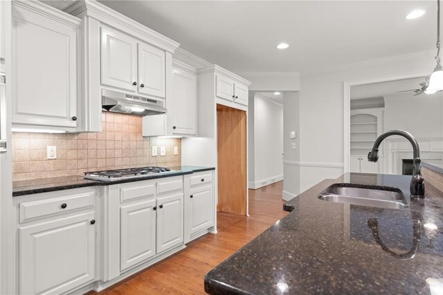 kitchen with dark stone counters, sink, light wood-type flooring, white cabinetry, and tasteful backsplash