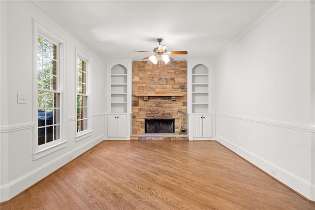 unfurnished living room with built in features, ornamental molding, a fireplace, and hardwood / wood-style floors