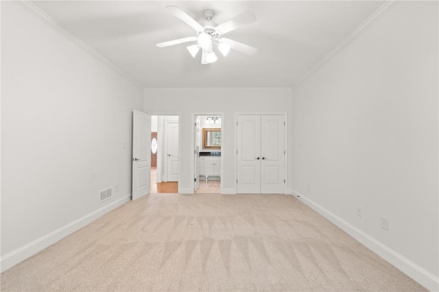 unfurnished bedroom with ornamental molding, ensuite bathroom, light colored carpet, and ceiling fan