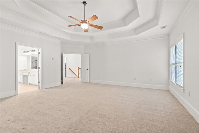 spare room featuring crown molding, a tray ceiling, and light colored carpet