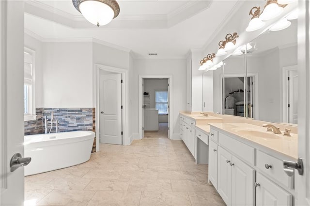 bathroom with a bathing tub, crown molding, vanity, and a raised ceiling