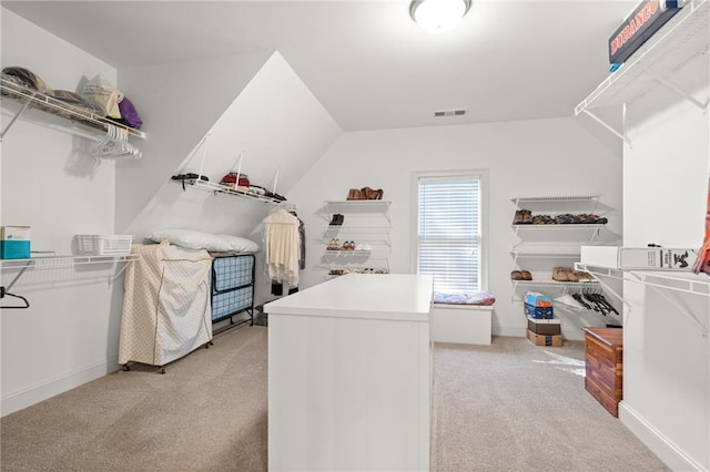 spacious closet with light colored carpet and vaulted ceiling