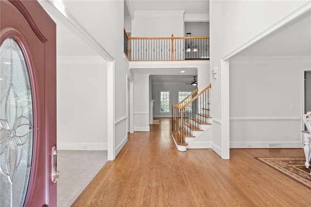 foyer with ceiling fan, ornamental molding, and light hardwood / wood-style flooring