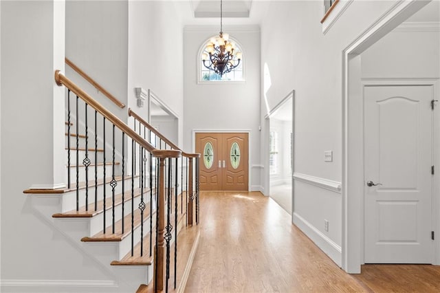 entryway featuring an inviting chandelier, a high ceiling, and light wood-type flooring