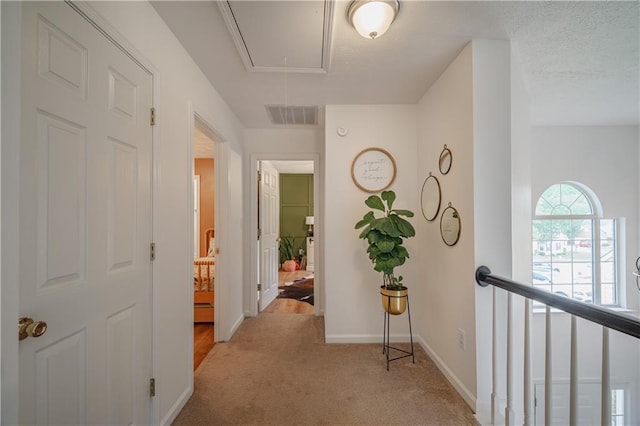 corridor featuring carpet floors, visible vents, attic access, an upstairs landing, and baseboards