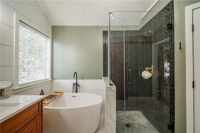 bathroom featuring lofted ceiling, vanity, tile walls, a freestanding bath, and a stall shower