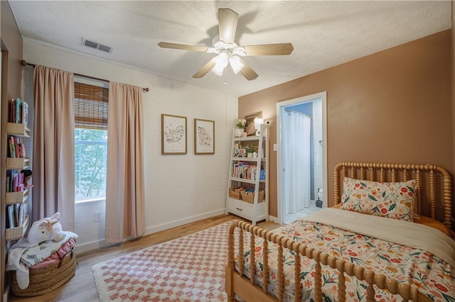 bedroom with a textured ceiling, wood finished floors, and visible vents