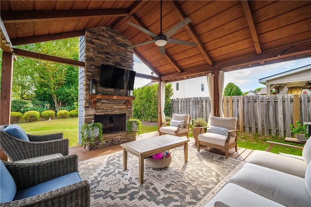 view of patio / terrace with ceiling fan, fence, a gazebo, and an outdoor living space with a fireplace