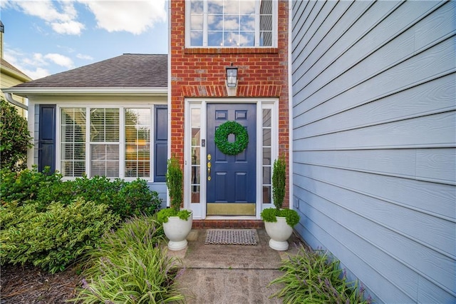 entrance to property with brick siding and roof with shingles