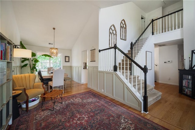 dining space featuring high vaulted ceiling, stairway, and wood finished floors