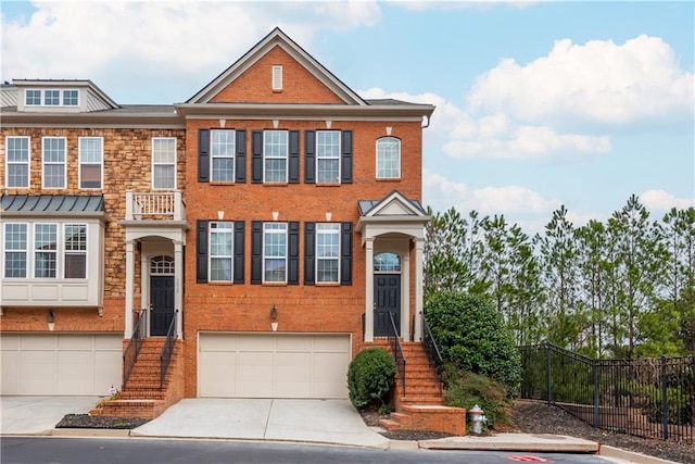 multi unit property featuring a garage, fence, concrete driveway, and brick siding