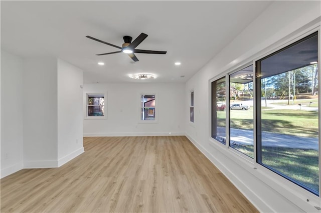 spare room featuring light wood finished floors, a wealth of natural light, and baseboards