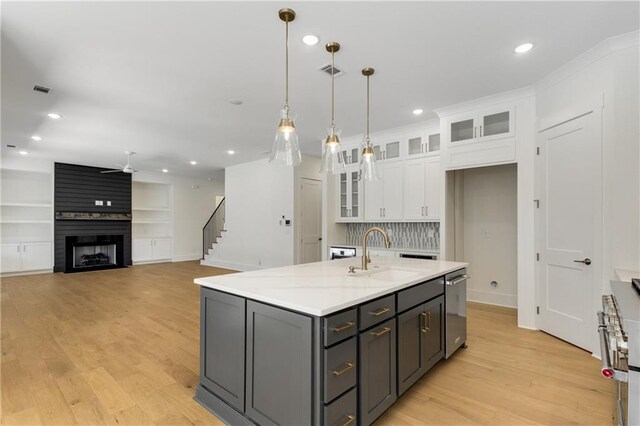 kitchen with beverage cooler, a center island with sink, light hardwood / wood-style flooring, white cabinets, and hanging light fixtures