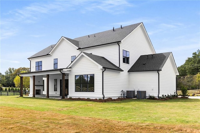 back of property with central AC unit, ceiling fan, and a yard