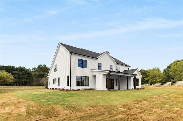 rear view of property with ceiling fan and a yard