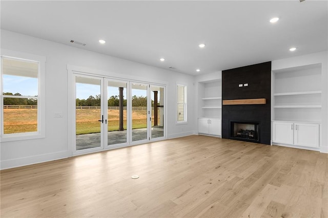 unfurnished living room featuring a fireplace, built in features, and light hardwood / wood-style floors