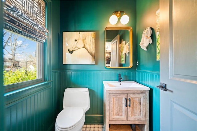 half bathroom with a wainscoted wall, vanity, and toilet