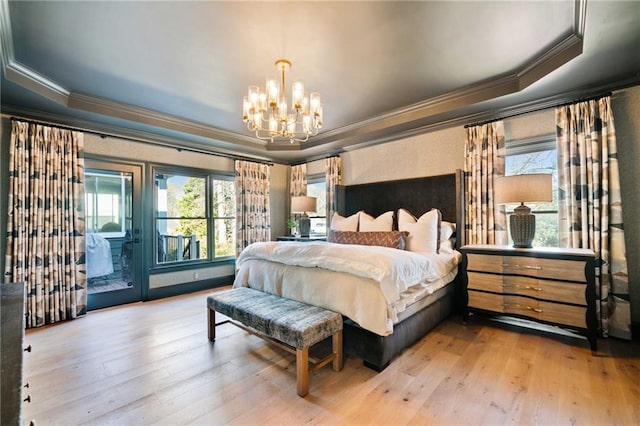 bedroom with a tray ceiling, an inviting chandelier, hardwood / wood-style flooring, and access to exterior