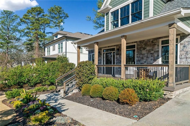 view of exterior entry with a porch and stone siding