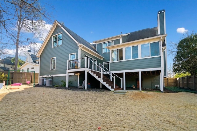 rear view of property featuring central air condition unit, fence, a sunroom, stairway, and a chimney