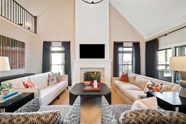 living room featuring high vaulted ceiling, a fireplace, wood finished floors, and crown molding