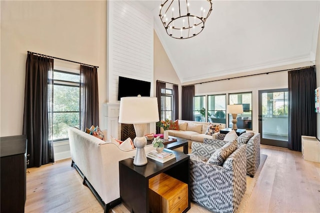 living room featuring high vaulted ceiling, a fireplace, light wood-style flooring, and a notable chandelier