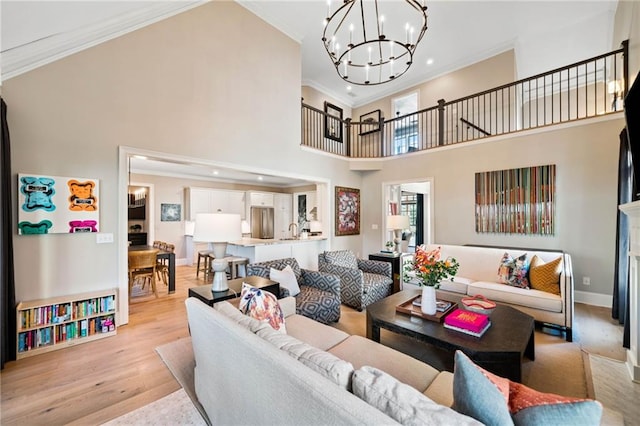 living area with a high ceiling, crown molding, light wood finished floors, and an inviting chandelier