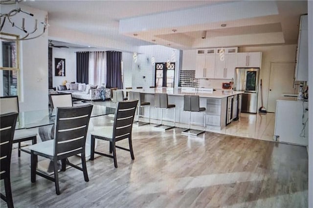 dining space featuring light hardwood / wood-style floors and a raised ceiling