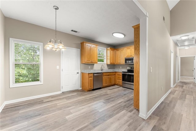 kitchen featuring appliances with stainless steel finishes, pendant lighting, light hardwood / wood-style floors, and a notable chandelier