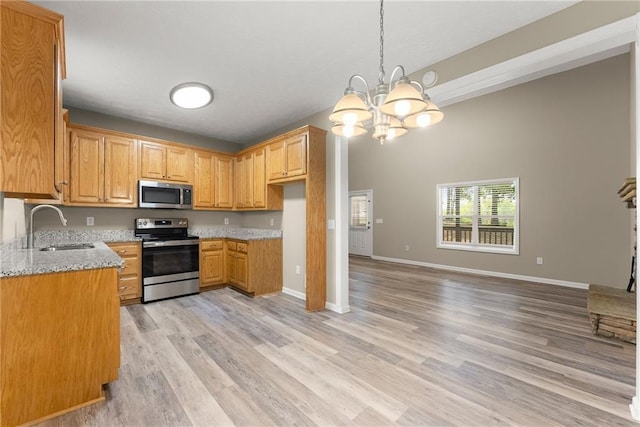 kitchen featuring light stone countertops, stainless steel appliances, sink, a chandelier, and light wood-type flooring