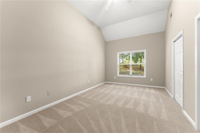 carpeted empty room with vaulted ceiling