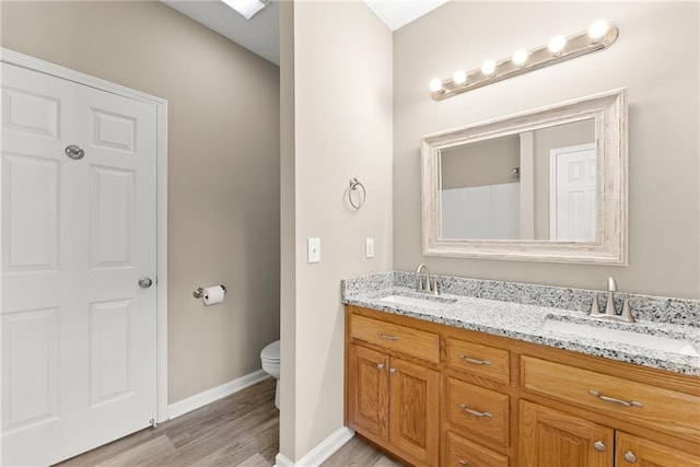 bathroom featuring wood-type flooring, toilet, and vanity