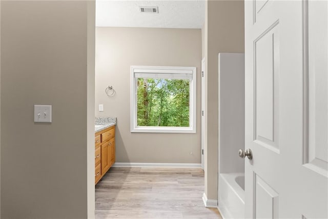 bathroom with hardwood / wood-style flooring, a bathing tub, a textured ceiling, and vanity