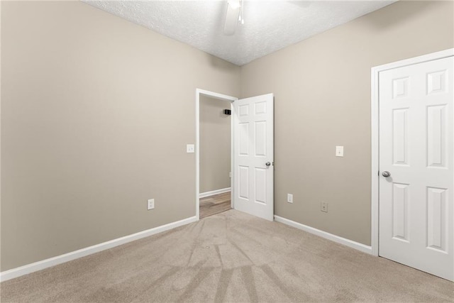 unfurnished bedroom featuring light colored carpet, ceiling fan, and a textured ceiling