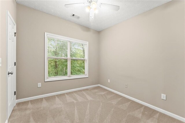 empty room featuring ceiling fan, light carpet, and a textured ceiling