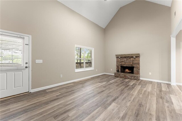 unfurnished living room featuring high vaulted ceiling, a fireplace, and light hardwood / wood-style floors