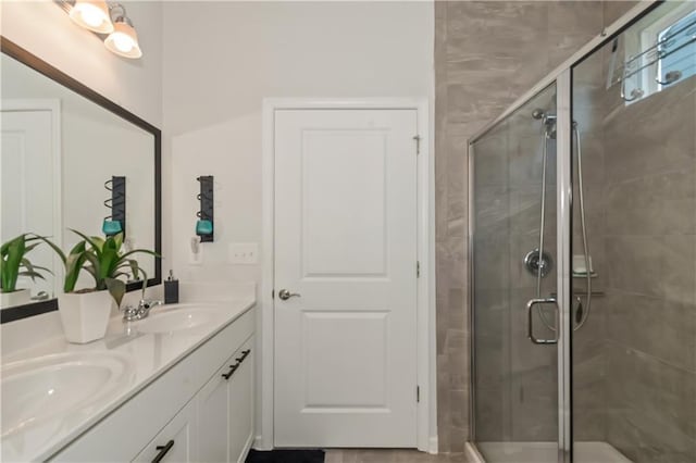 full bath featuring double vanity, a stall shower, and a sink