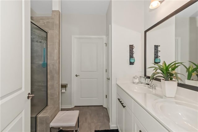 bathroom with a tile shower, double vanity, and a sink