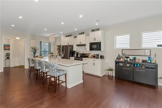 kitchen featuring a breakfast bar area, dark wood-type flooring, stainless steel appliances, white cabinetry, and a sink