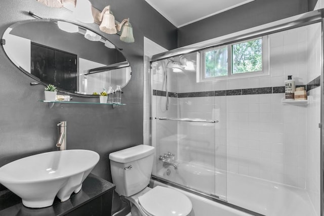 full bathroom with sink, toilet, and combined bath / shower with glass door