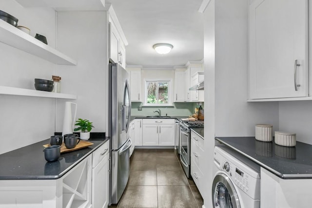 kitchen featuring appliances with stainless steel finishes, washer / clothes dryer, sink, dark stone countertops, and white cabinets