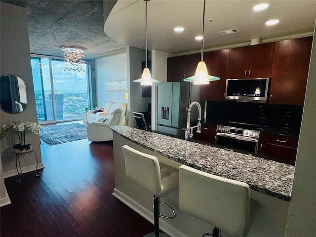 400 W Peachtree St NW Unit 3412, Atlanta, GA 30308 - kitchen with appliances with stainless steel finishes, a wall of windows, dark wood-type flooring, dark countertops, and a kitchen breakfast bar