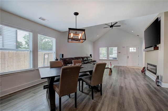 dining area featuring baseboards, visible vents, a glass covered fireplace, dark wood-type flooring, and heating unit