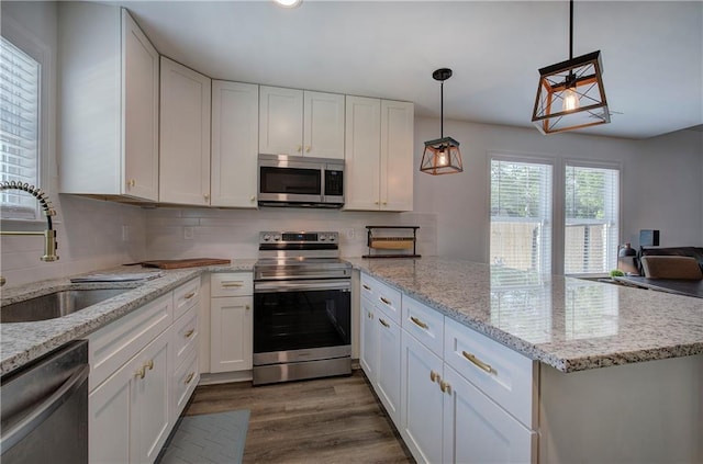 kitchen featuring decorative light fixtures, dark wood finished floors, stainless steel appliances, white cabinetry, and a sink