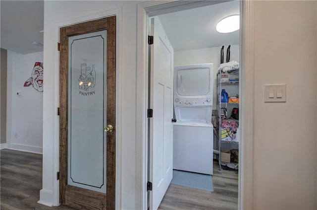 hallway featuring stacked washer / dryer, baseboards, and wood finished floors