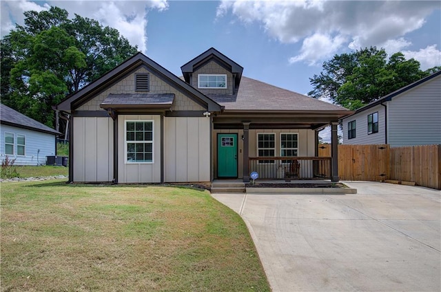 view of front of home with board and batten siding, a front yard, covered porch, and fence