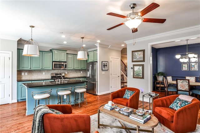 living area with a ceiling fan, recessed lighting, light wood-type flooring, ornamental molding, and stairway