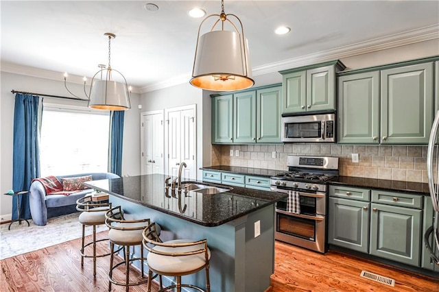 kitchen featuring a sink, appliances with stainless steel finishes, light wood-style flooring, and visible vents