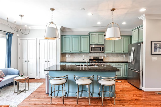 kitchen featuring a sink, appliances with stainless steel finishes, crown molding, and green cabinets