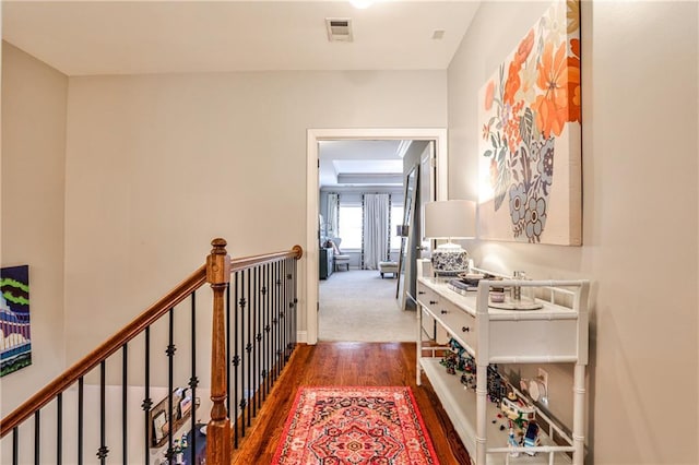 corridor with baseboards, an upstairs landing, wood finished floors, and visible vents